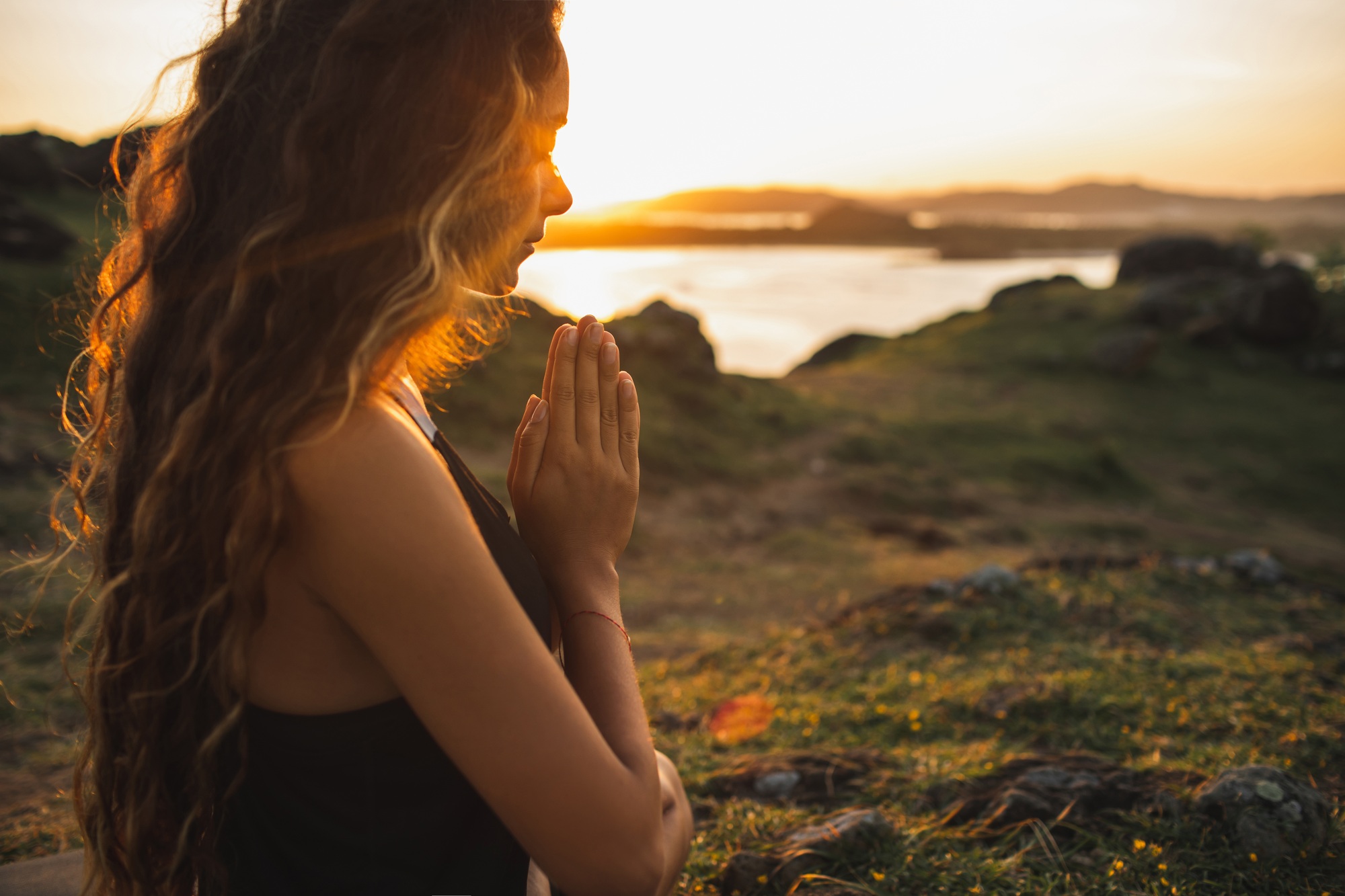 Woman praying alone at sunrise. Nature background. Spiritual and emotional concept. Sensitivity